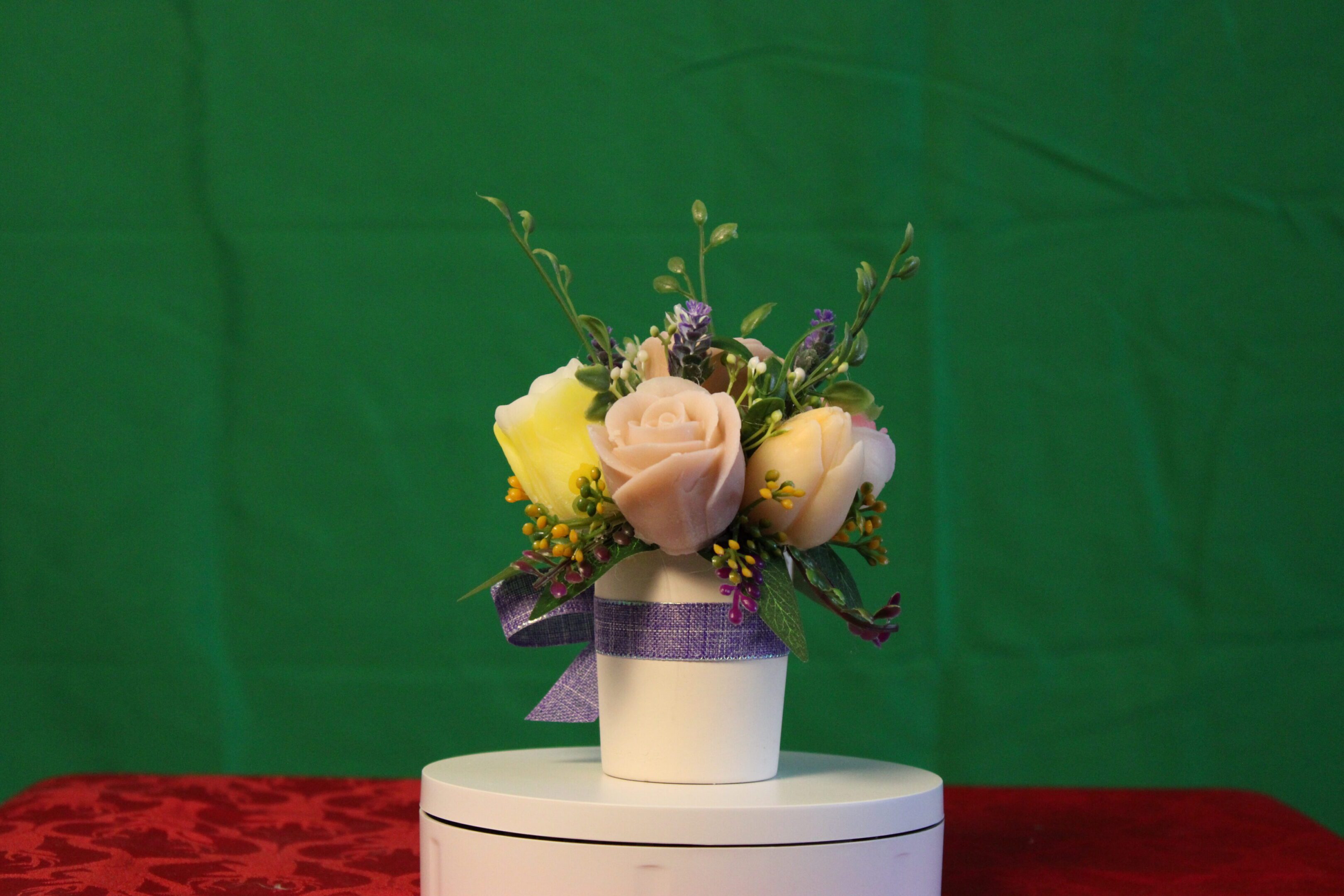 Cream roses in white vase with purple ribbon