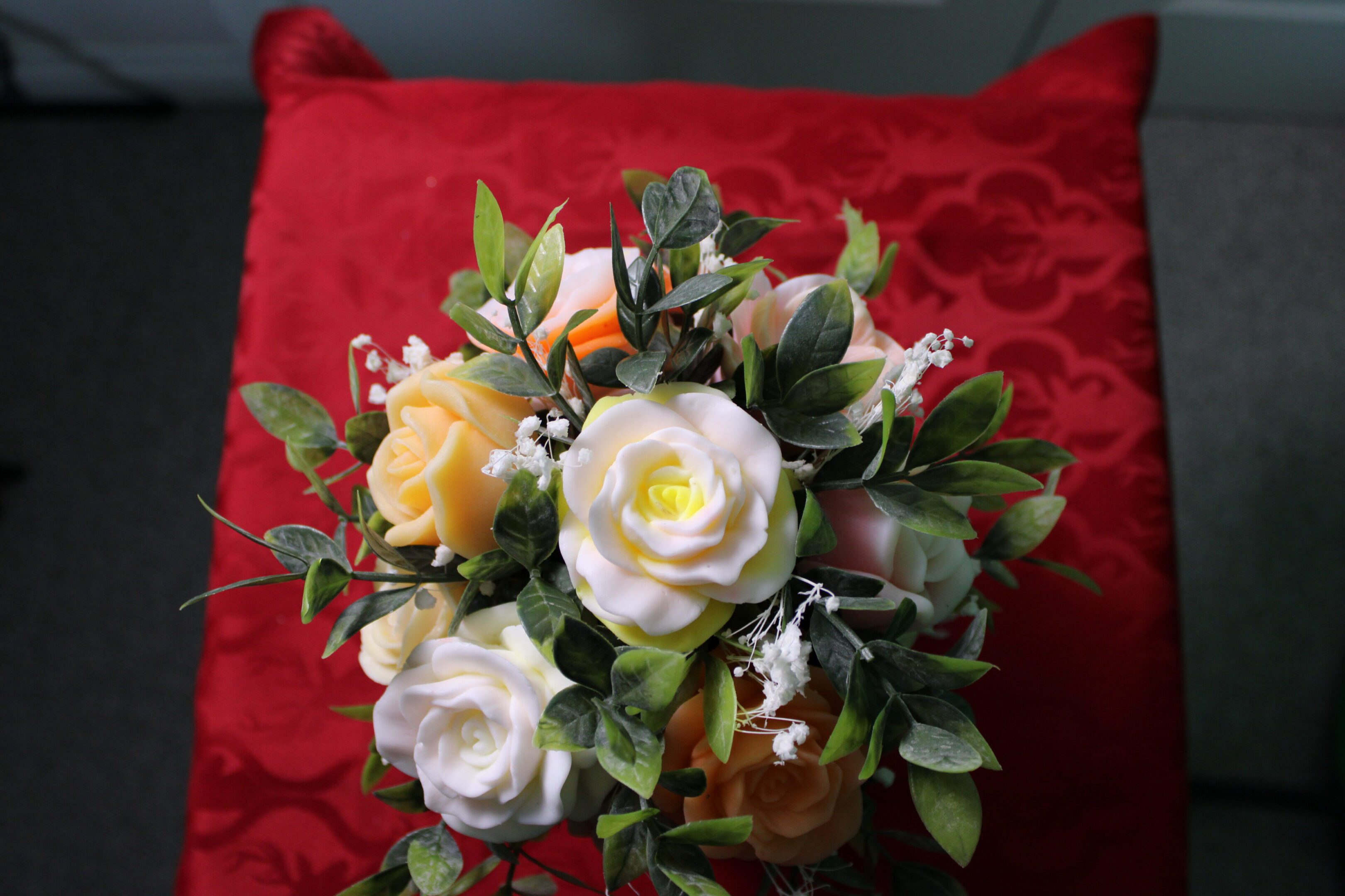 White and yellow rose bouquet on red cushion