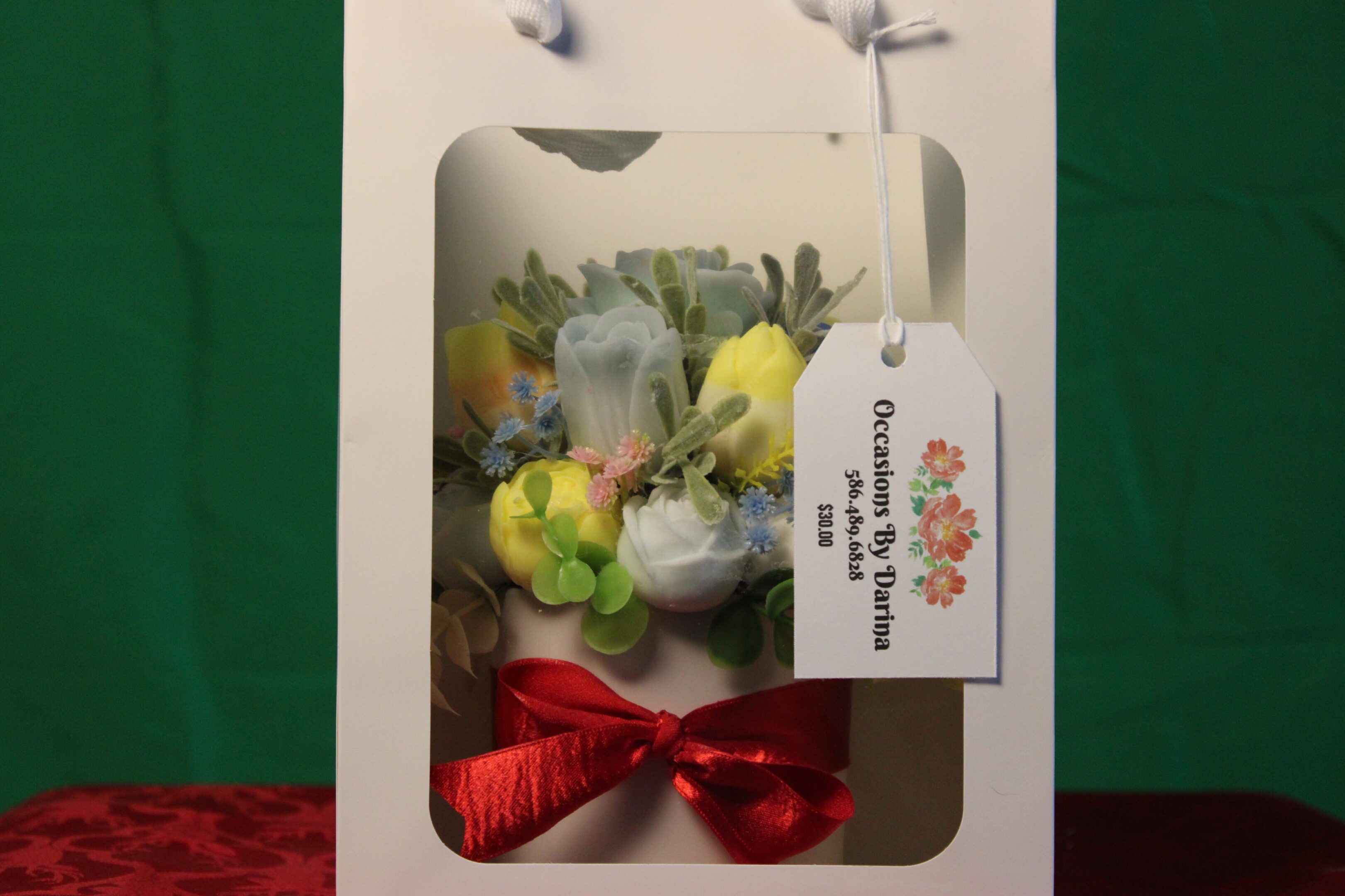 White gift box with artificial flowers, red bow
