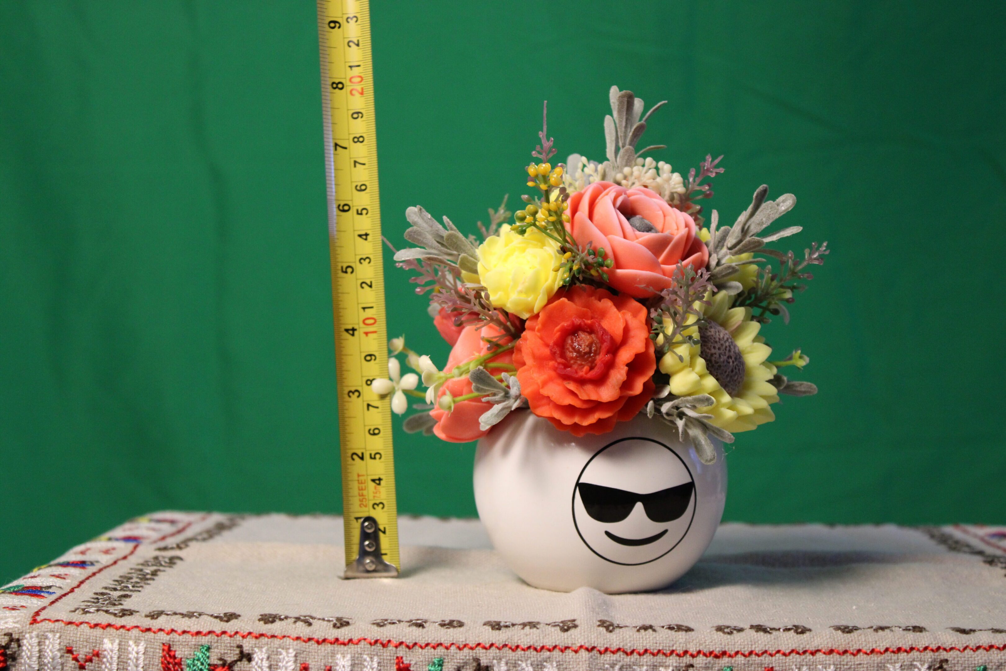 White smiley vase holding colorful faux flowers