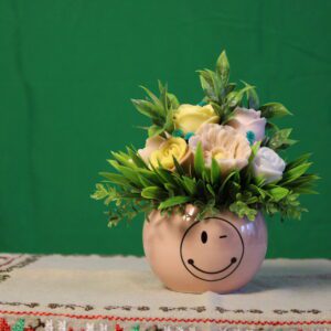 Smiling face vase with artificial flower arrangement